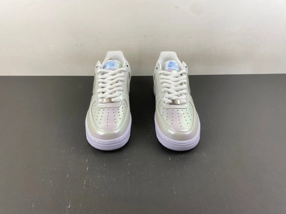 A pair of pale iridescent low-top sneakers on a dark surface
